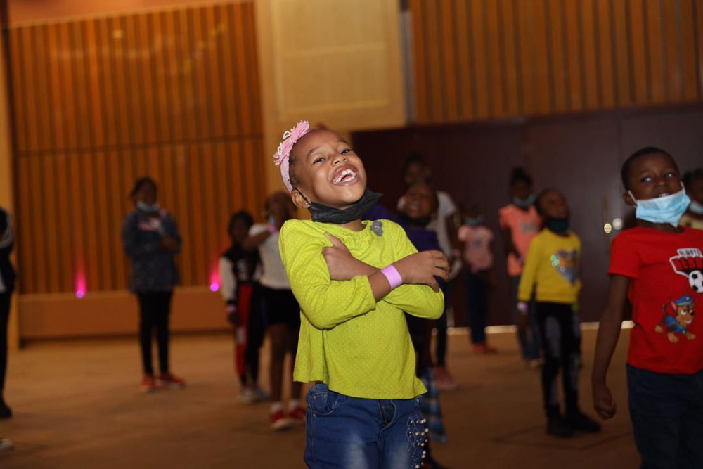 A young participant laughing during a workshop session on the Hall stage.