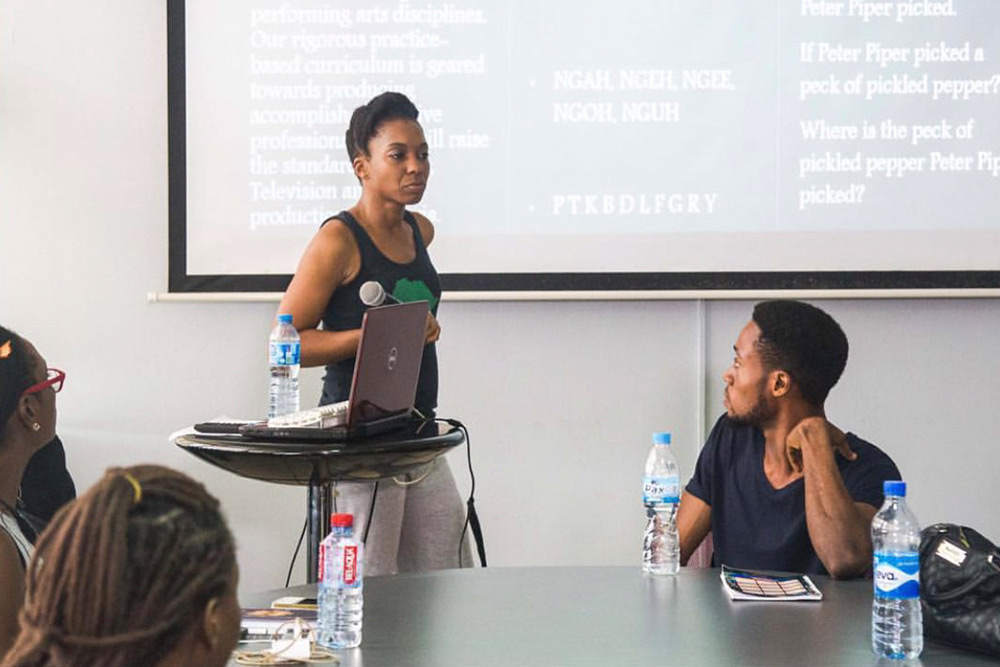 An instructor leads a seminar at a projector screen while students work at the table.