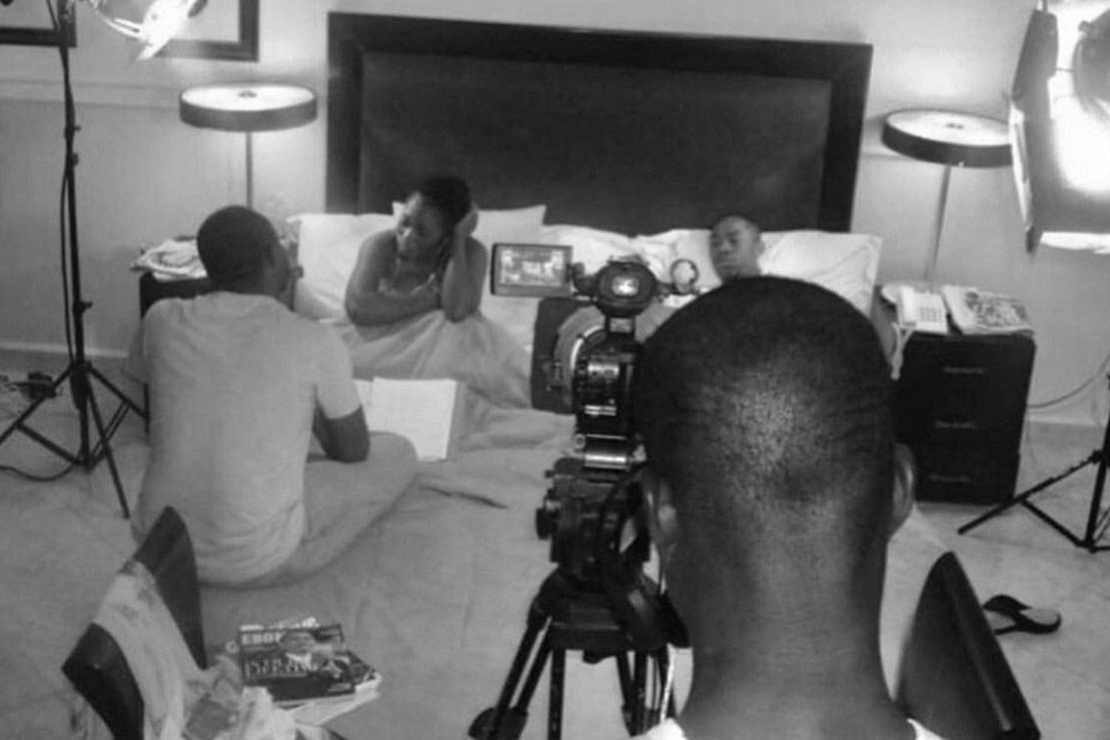 A black-and-white frame of a screen-craft class: a camera on a tripod trained on a student performing to it.