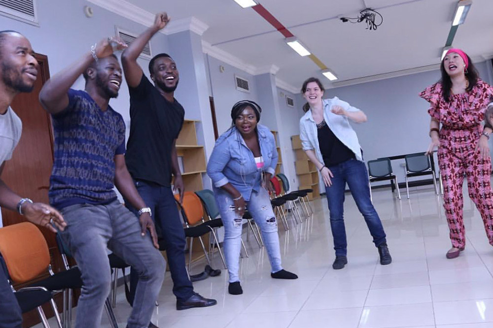 Four students mid-exercise in a bright studio, arms raised, caught in movement.